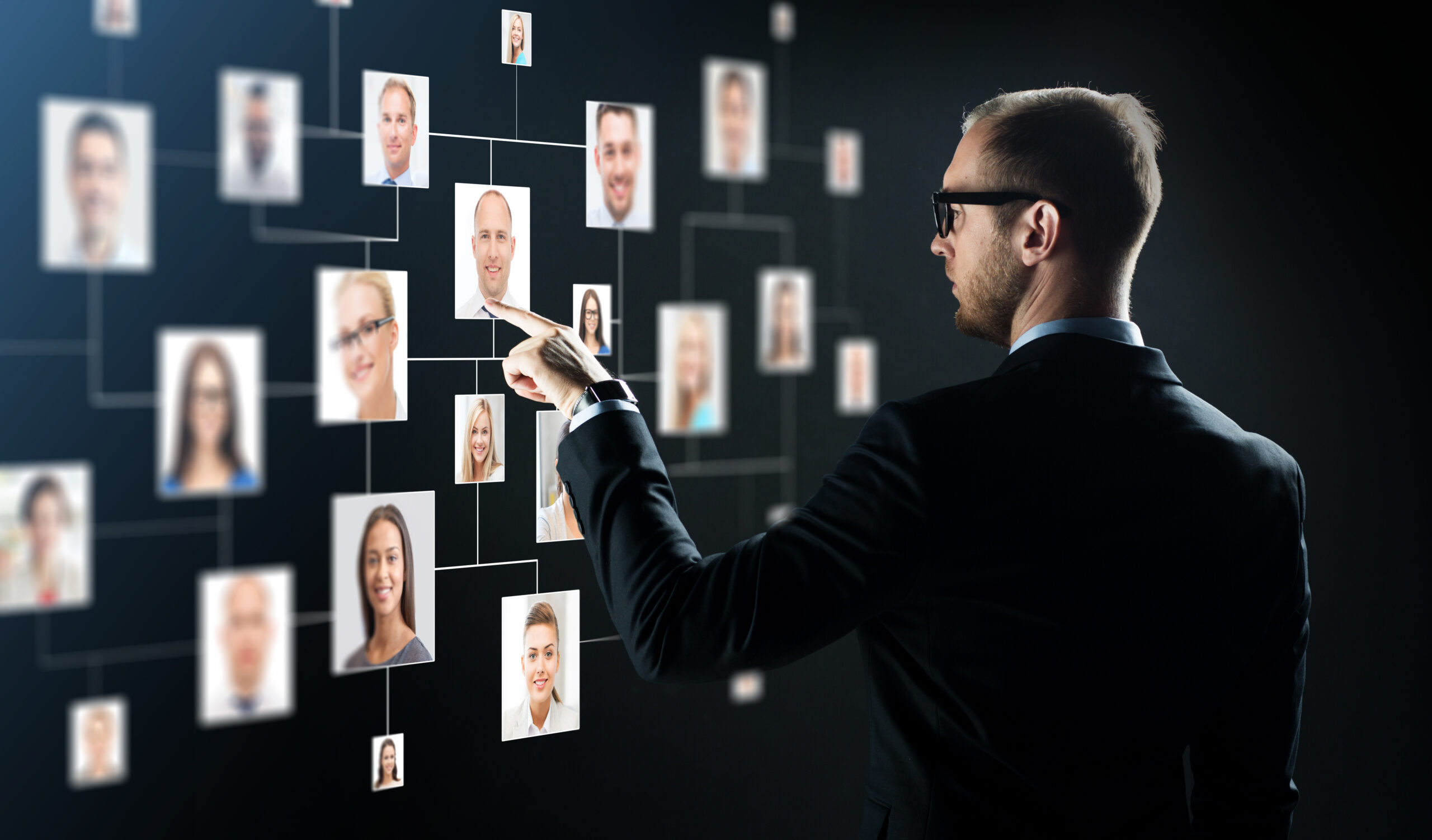 business, people, technology, hiring and employment concept - businessman in suit and glasses pointing finger to contact icons over black background